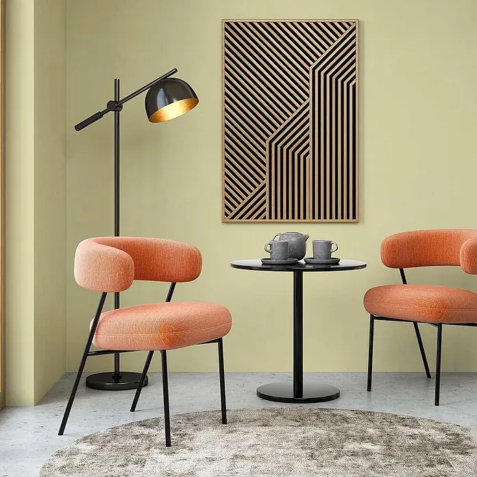 Tadessi Wandfarbe Blassgrün - Grün, Matt, 1 l - Moderne geometrische Wandkunst mit schwarzen und Holzstreifen, über zwei pfirsichfarbenen Stühlen und einem Beistelltisch.