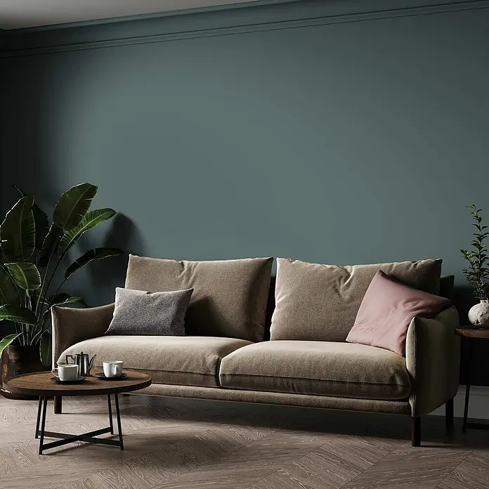 Tadessi Wandfarbe Smaragd - Grün, Matt, 1 l - Braunes Stoffsofa mit Kissen in einem modernen Wohnzimmer.