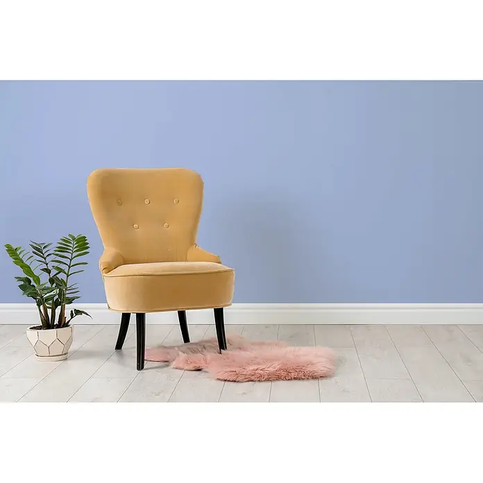 Tadessi Wandfarbe Aura Indigo - Lila, Matt, 2,5 l - Gelber Samtsessel in einem Raum mit einer grünen Pflanze und einem rosa Teppich.