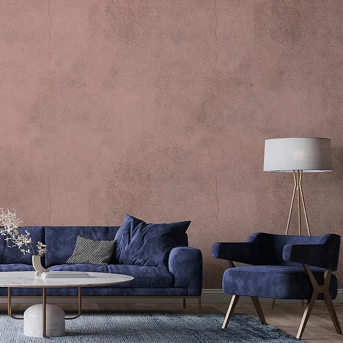 Tadessi Wandfarbe Rosébeige - Rosa, Matt, 5 l - Ein blaues Samtsofa und ein Sessel schmücken ein modernes Wohnzimmer, ergänzt durch einen Marmor-Couchtisch und eine goldene Stehlampe.