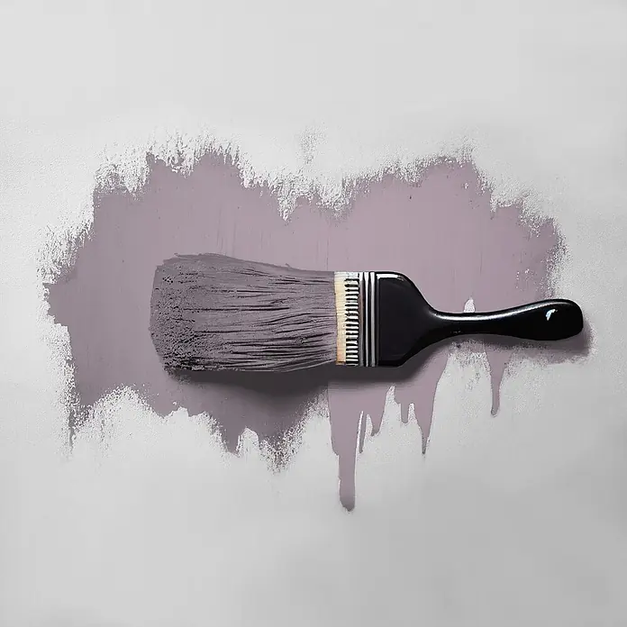 Tadessi Wandfarbe Mauve - Lila, Matt, 2,5 l - Pinsel mit schwarzem Griff und hellen Borsten trägt gedämpfte violette Farbe auf eine helle Wand auf, zeigt Striche und Tropfen.