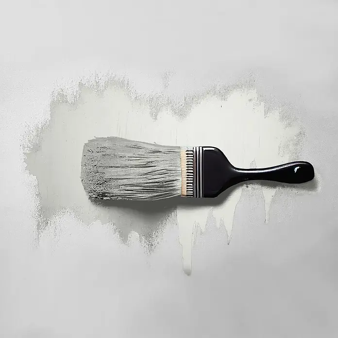 Tadessi Wandfarbe Alabaster - Beige, Matt, 5 l - Pinsel mit schwarzem Griff trägt graue Farbe auf eine strukturierte Wand auf, mit Farbtropfen.