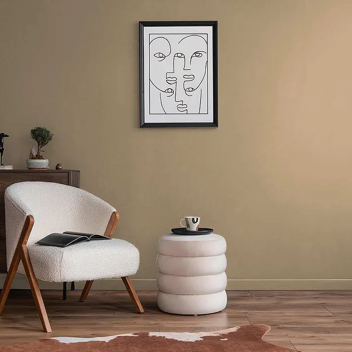 Tadessi Wandfarbe Vanillebeige - Beige, Matt, 5 l - Cremefarbener, gestapelter Ringhocker mit Tasse und Tablett, als Beistelltisch in einem modernen Wohnzimmer.