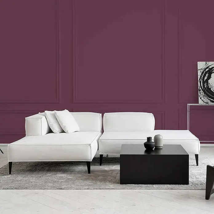 Tadessi Wandfarbe Aubergine - Violett, Matt, 1 l - Weißes Modulsofa mit schwarzem Couchtisch in einem modernen Wohnzimmer mit violetter Wandvertäfelung.