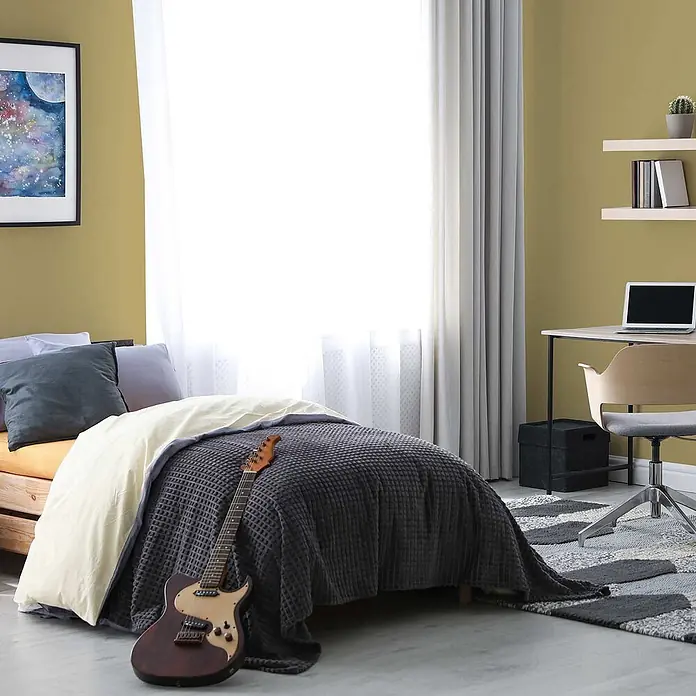 Tadessi Wandfarbe Wüstensand - Grün, Matt, 2,5 l - Modernes Schlafzimmer mit Bett, grauer Waffeldecke, cremefarbenem Bettbezug und einer braunen E-Gitarre. Ein Schreibtisch mit Laptop ist in der Nähe.