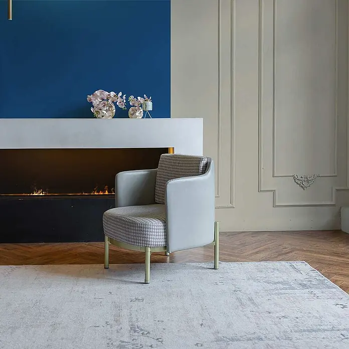 Tadessi Wandfarbe Sandgrün - Beige, Matt, 1 l - Moderner Sessel mit hellgrauem Kunstleder und Hahnentritt-Stoffbezug, mit hellgrünen Beinen, in Wohnzimmerumgebung.