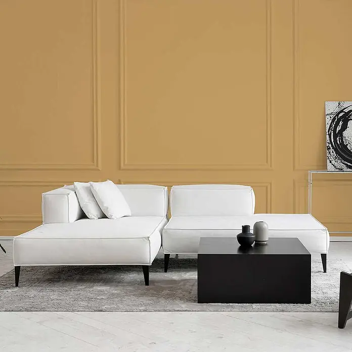 Tadessi Wandfarbe Safrangelb - Orange, Matt, 5 l - Weißes modulares Sofa mit schwarzen Beinen und ein quadratischer schwarzer Couchtisch in einem modernen Wohnzimmer.
