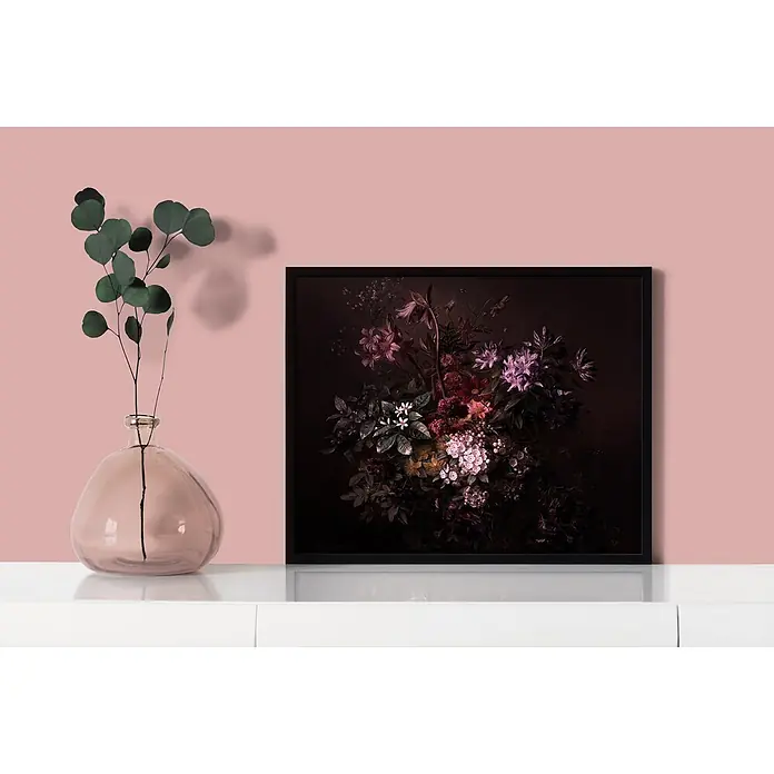 Tadessi Wandfarbe Purderrosa Dunkel - Rosa, Matt, 2,5 l - Gerahmtes dunkles Blumenkunstwerk mit schwarzem Rahmen, auf weißer Konsole neben Glasvase mit Eukalyptus vor rosa Wand.