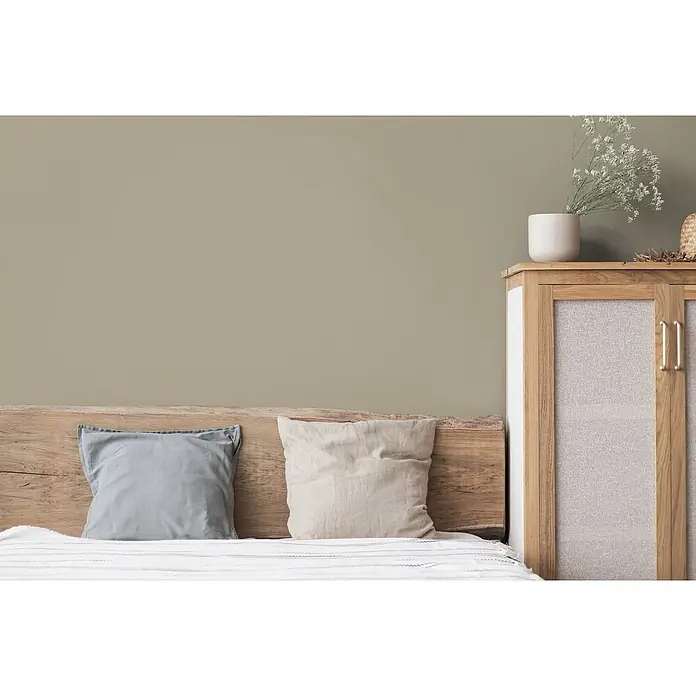 Tadessi Wandfarbe Dunkelgrau Mocha - Braun, Matt, 2,5 l - Eine gemütliche Schlafzimmerszene mit Holzbett, hellen Kissen und Nachttisch. Die Wand ist in einem warmen, gedämpften Olivton gestrichen.