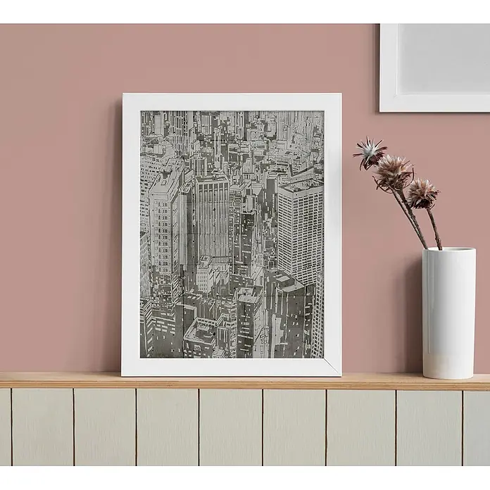 Tadessi Wandfarbe Rosébraun - Braun, Matt, 2,5 l - Weiß gerahmter Kunstdruck mit monochromer Stadtlandschaft auf einem Holzregal.