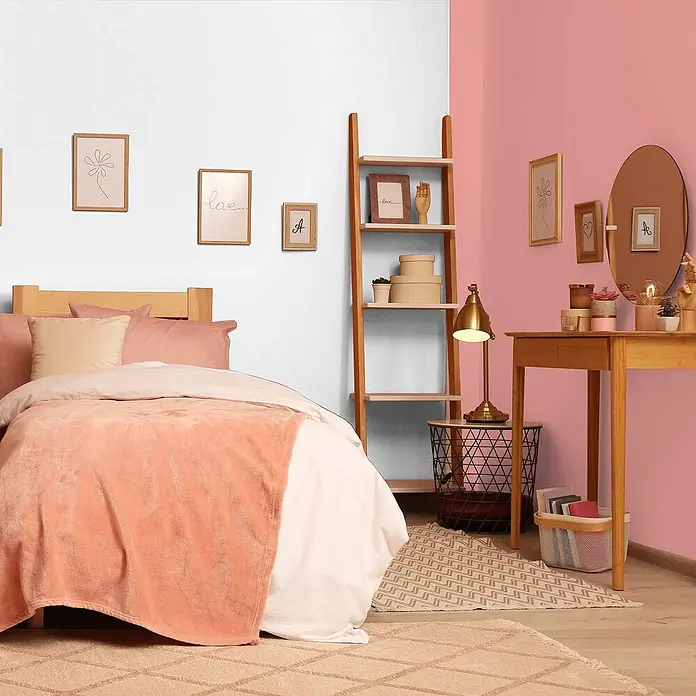 Tadessi Wandfarbe Erdbeerrosa - Pink, Matt, 1 l - Eine weiche, korallenfarbene Kuscheldecke liegt auf einem Bett mit heller Bettwäsche in einem gemütlichen Schlafzimmer.