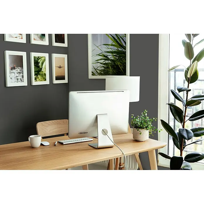 Tadessi Wandfarbe Nebelgrau - Grau, Matt, 5 l - Ein heller Holzschreibtisch mit silbernem Computer, weißer Tastatur, Maus und weißer Lampe im Home Office.