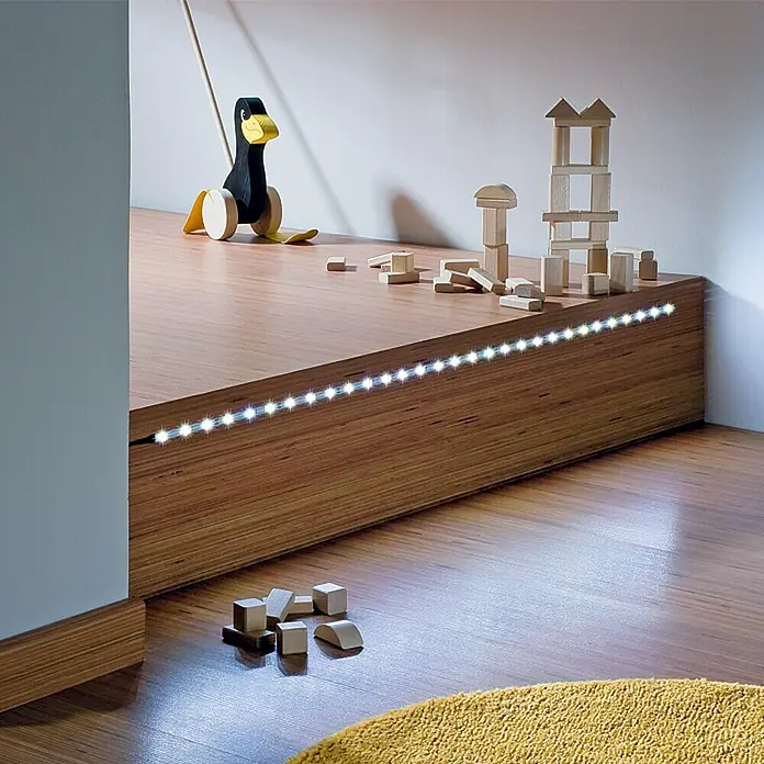 Tween Light LED-Band - Länge: 10 m, Lichtfarbe: Warmweiß, 13 W - Plattform mit LED-Beleuchtung, Holzspielzeug und einer Holzente, die eine warme, einladende Atmosphäre schafft.