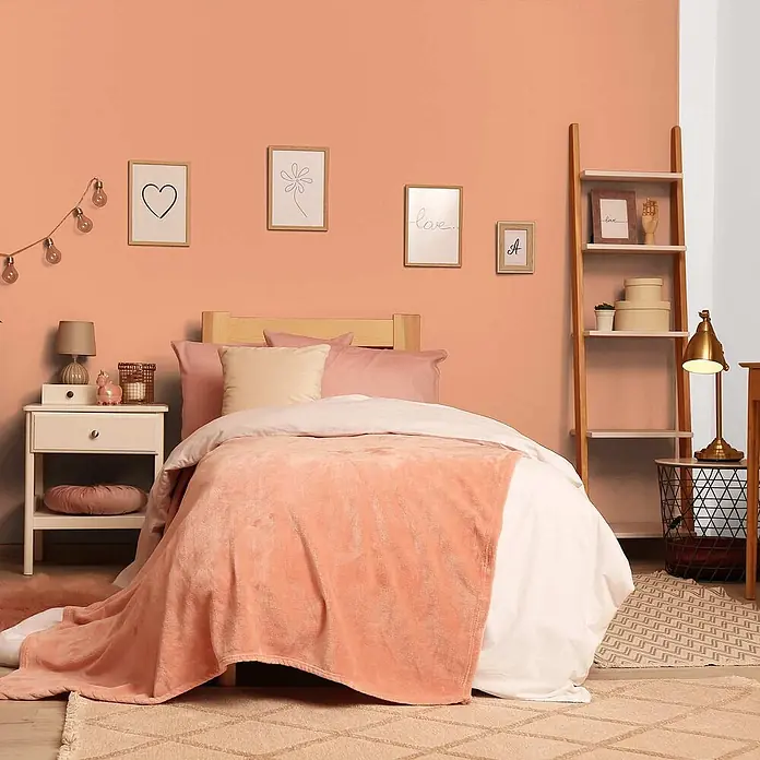 Tadessi Wandfarbe Melone - Orange, Matt, 1 l - Weiche, korallfarbene Decke auf einem Bett in einem gemütlichen Schlafzimmer.