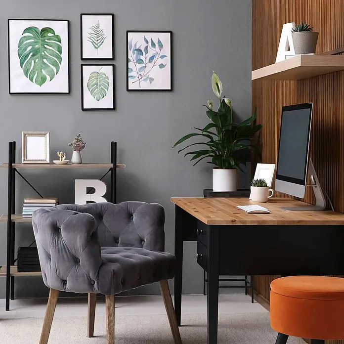 Tadessi Wandfarbe Silbergrau - Grau, Matt, 2,5 l - Ein grauer Samt-Sessel mit Knopfheftung und Holzbeinen, platziert in einem modernen Home-Office.