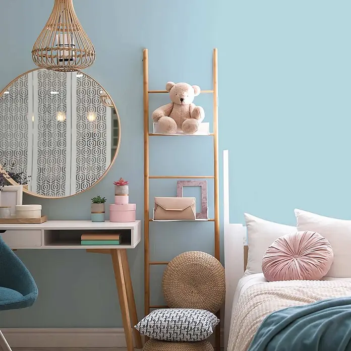 Tadessi Wandfarbe Wasserblau - Blau, Matt, 2,5 l - Bambus-Leiterregal in hellblauem Zimmer, mit Teddybär, Clutch und Bilderrahmen. Geflochtene Poufs und Kissen am Fuß.