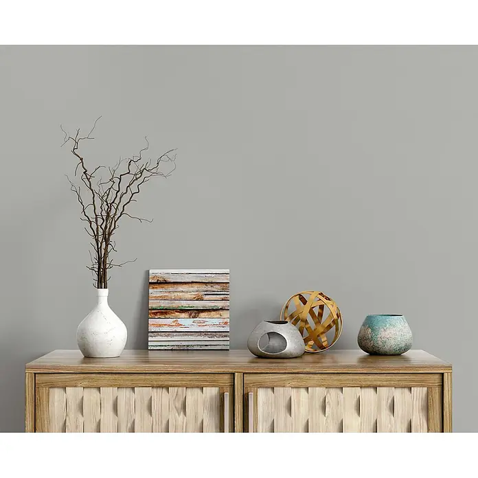 Tadessi Wandfarbe Sanftgrau - Grau, Matt, 5 l - Helles Holz Sideboard mit strukturierten Türen, dekoriert mit Vase, Bild und Zierobjekten.