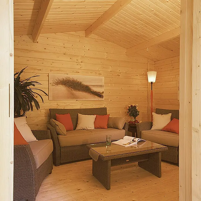 Kiehnholz Gartenhaus Östersund - Außenmaß inkl. Dachüberstand (B x T): 437 x 423 cm, Holz, Natur - Gemütliches Wohnzimmer mit Holzvertäfelung, ausgestattet mit Rattansesseln und einem Couchtisch mit Glasplatte.