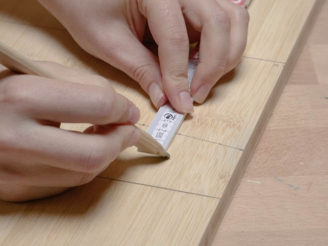 Maße werden auf einem Holzbrett mit Bleistift markiert