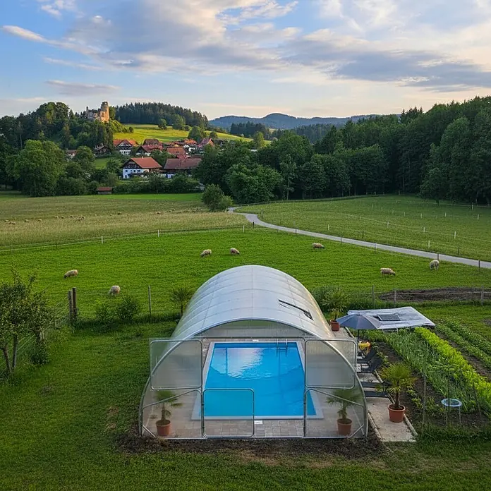 Garten Dream Poolüberdachung Serena, 4mm Polycarbonate - L x B x H: 1.000 x 400 x 230 cm - Gewölbte, transparente Poolüberdachung schützt einen blauen Swimmingpool in einer malerischen Außenanlage.