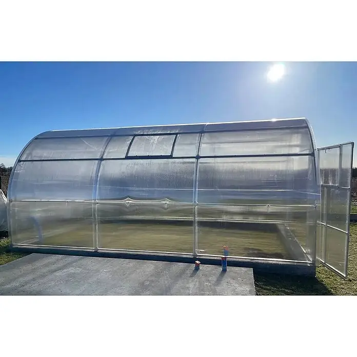 Garten Dream Gewächshaus Oasis, 10mm Polycarbonat - Außenmaß inkl. Dachüberstand (B x T): 400 x 600 cm, Material Seitenwand: Kunststoff, 10 mm, Silber - Gewölbtes Gewächshaus aus klarem Kunststoff mit offener Tür und Dachluke, in der Sonne stehend.