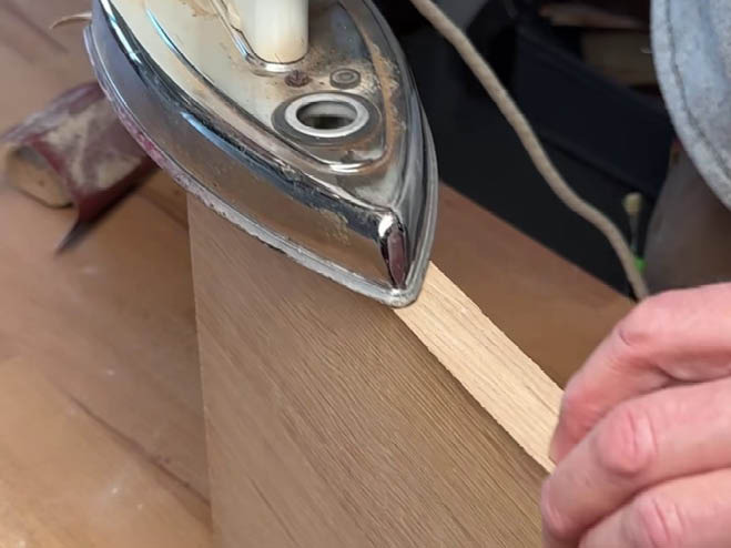 Mit einem Bügeleisen wird eine Kante auf ein Holzbrett gebügelt