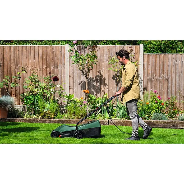 Bosch Elektro-Rasenmäher EasyRotak 32-235 - 1.200 W, Schnittbreite: 32 cm - Ein Mann schiebt einen grünen Elektromäher über einen üppigen grünen Rasen in einem Garten.