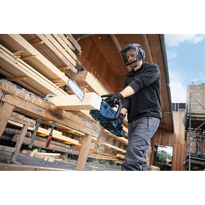 Bosch Professional AMPShare 18V Akku-Kettensäge GKE18V-30 - 18 V, Ohne Akku, Schwertlänge: 30 cm - Mann in Schutzkleidung schneidet Holz mit blauer und schwarzer Bosch Kettensäge, Späne fliegen.
