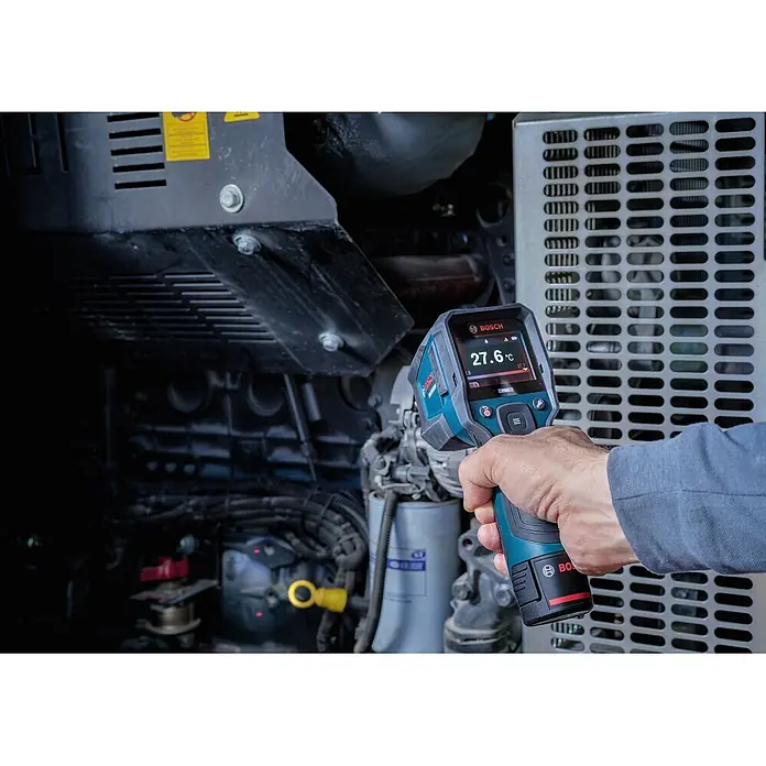 Bosch Professional Thermodetektor Pro GIS12V-800-16 - Messbereich Temperatur: -40 °C - 800 °C, Mit Batterien - Eine Hand hält eine blau-schwarze Bosch Wärmebildkamera, die 27,6 °C an einer Industriemaschine anzeigt.