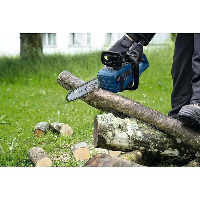 Bosch Professional AMPShare 18V Akku-Kettensäge GKE18V-30 - 18 V, Ohne Akku, Schwertlänge: 30 cm - Blaue Bosch Kettensäge sägt einen Baumstamm im Freien. Holzspäne fliegen beim Gebrauch.