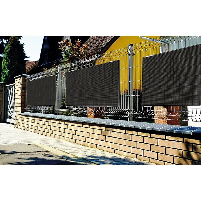Schwaiger Halterung - Passend für: Solarmodule - Dunkelgrauer gewebter Sichtschutz auf einem Metallzaun über einer Ziegelmauer.