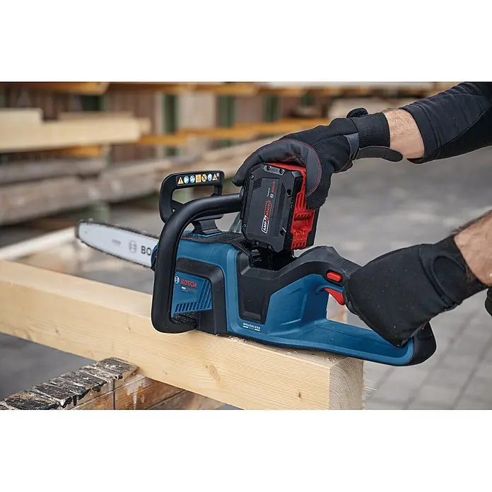 Bosch Professional AMPShare 18V Akku-Kettensäge GKE18V-30 - 18 V, Ohne Akku, Schwertlänge: 30 cm - Behandschuhte Hände setzen einen rot-schwarzen Akku in eine blau-schwarze Bosch Akku-Kettensäge ein, die auf einem Holzbalken liegt.