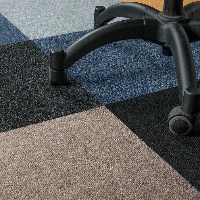 Bricoflor Teppichfliese - Breite: 50 cm, Nadelfilz, Polypropylen, blau - Schwarzes fünfstrahliges Bürostuhlgestell mit Rollen auf mehrfarbigen Teppichfliesen.