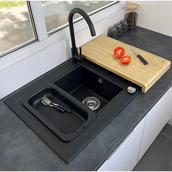 Carea Einbauspüle Muscade - 86 x 50 cm, Schwarz, Mit Schneidebrett & Besteckschale - Schwarzes Spülbecken mit schwarzem Wasserhahn, Bambus-Schneidebrett und Abtropfkorb auf dunkler Arbeitsplatte.