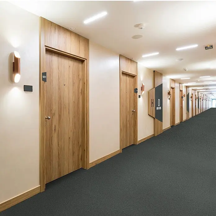 Vinylboden CV-Belag - 1.400 x 100 cm, Mira 990D - Dunkelgrauer, strukturierter Teppichboden in einem langen Hotel- oder Apartmentflur.