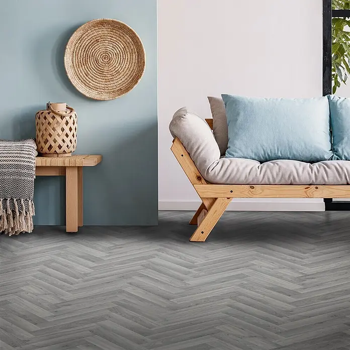 Vinylboden CV-Belag - 400 x 200 cm, Oak Chevron 907M - Grauer Fischgrätboden in einem modernen Wohnzimmer. Die strukturierten Holzoptik-Dielen verleihen dem Raum eine stilvolle Note.