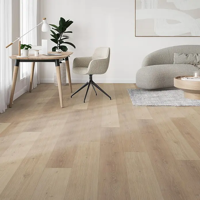 Parador Vinylboden Trendtime 6 - Eiche Natural Mix Grau, Schlossdiele, 2.200 x 216 x 9,6 mm - Hellbraune Holzplankenboden in einem modernen Raum mit Schreibtisch und Sofa verlegt.