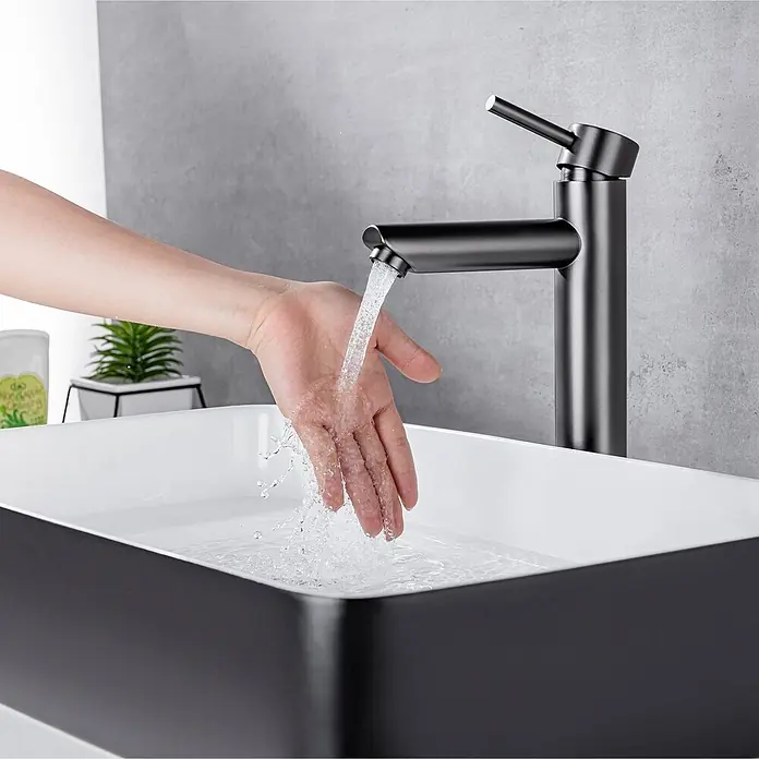LOMAZOO Waschtischarmatur LMZ-TESS - Gunmetal - Moderner schwarzer Wasserhahn und rechteckiges schwarz-weißes Waschbecken mit einer Hand unter fließendem Wasser.