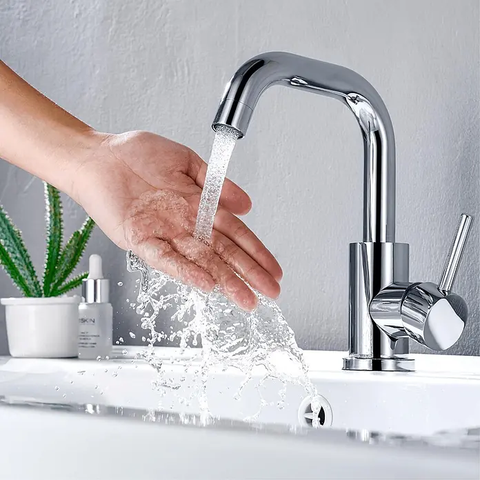 LOMAZOO Waschtischarmatur LMZ-ROSELY - Chrom - Verchromter Wasserhahn spendet Wasser in eine Hand über einem Waschbecken.