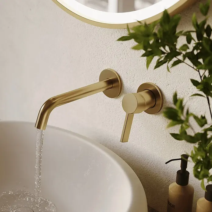 LOMAZOO Waschtischarmatur LMZ-VELAR - Gold - Goldene Wandarmatur mit Hebelgriff und fließendem Wasser über einem weißen Waschbecken.