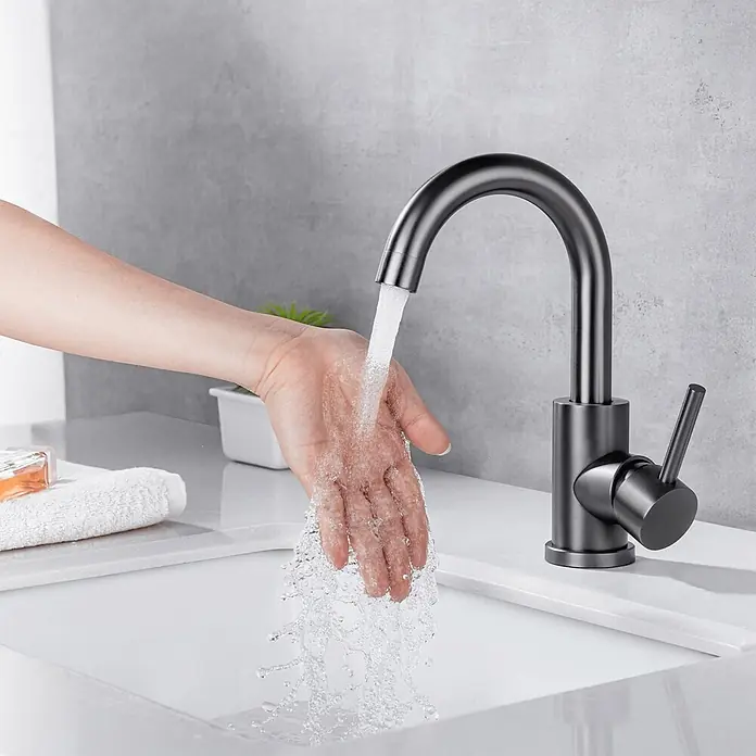 LOMAZOO Waschtischarmatur LMZ-CHLOE - Gunmetal - Mattschwarze Armatur, die Wasser über eine Hand in ein weißes Waschbecken laufen lässt.