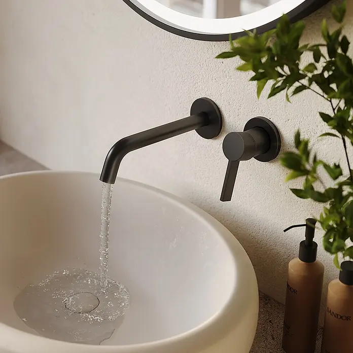 LOMAZOO Waschtischarmatur LMZ-CENTAURI - Schwarz - Mattschwarze Wandarmatur und Griff über einem weißen Waschbecken mit fließendem Wasser.