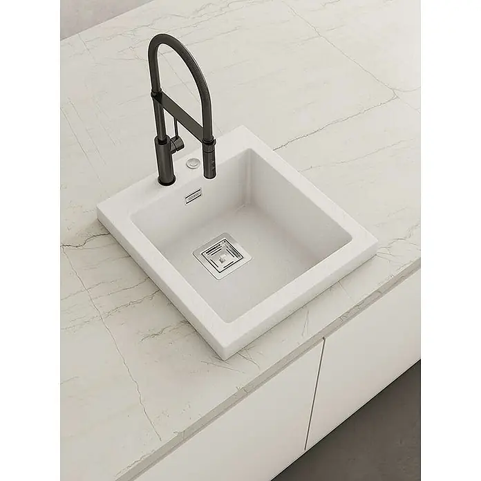 Poalgi Einbauspüle Kobus - 47 x 52 cm, Verbundwerkstoff - Weiße Küchenspüle mit schwarzem Wasserhahn, in eine marmorierte Arbeitsplatte eingebaut.