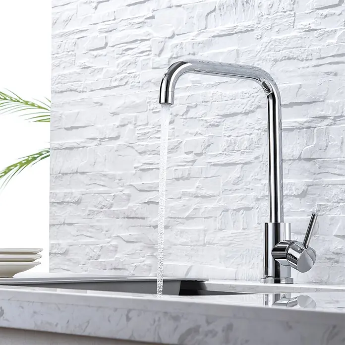 LOMAZOO Spültischarmatur LMZ-HYBRIS - Chroom - Polierter Chrom-Küchenarmatur mit Wasserstrahl in ein modernes Spülbecken, vor einer strukturierten weißen Wand.