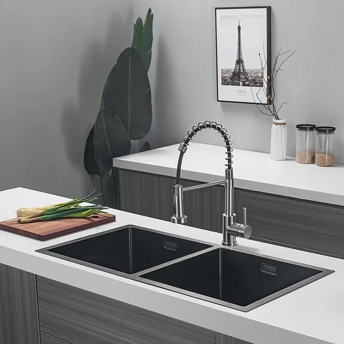 LOMAZOO Waschbecken LMZ-AQUARIUS - B x L: 45 x 87,5 cm, Mit Überlauf, Gunmetal - Eine moderne Küche zeigt eine schwarze Doppelspüle mit gebürsteter Edelstahl-Ausziehbrause, in eine weiße Arbeitsplatte integriert.