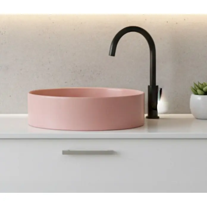 Kreabad Waschbecken - Hahnloch: Ohne, Ohne Überlauf, Rosa - Rundes pinkfarbenes Aufsatzwaschbecken mit matt-schwarzem Wasserhahn auf weißem Waschtisch.