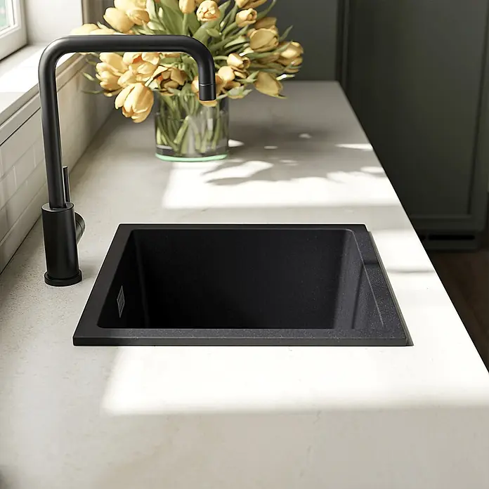LOMAZOO Waschbecken LMZ-PEDRI - Mit Überlauf, Schwarz - Schwarzes Granitspülbecken und passende matte schwarze Armatur in einer hellen Arbeitsplatte, natürlich beleuchtet.