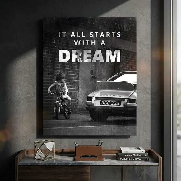 Dotcomcanvas Decopanel - It all starts with a dream, B x H: 40 x 50 cm - Schwarz-weiß gerahmter Druck: Kind auf Fahrrad neben Porsche, mit Text „IT ALL STARTS WITH A DREAM“, über einem Schreibtisch.