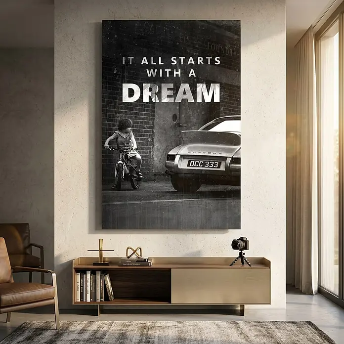 Dotcomcanvas Decopanel - It All Starts with a Dream, B x H: 58 x 90 cm - Großer gerahmter Kunstdruck mit Kind auf Fahrrad neben einem Porsche und dem Text „IT ALL STARTS WITH A DREAM“ über einem Schrank.