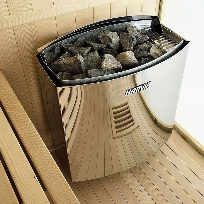 Artsauna Elementsauna Espoo - L x B x H: 150 x 150 x 200 cm - Ein verchromter Harvia Saunaofen mit Steinen, der das hölzerne Sauna-Interieur reflektiert.